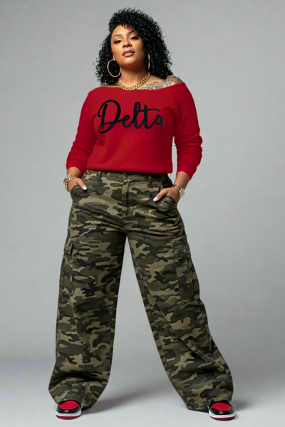 Person wearing a red sweatshirt with 'Delta' text and camouflage pants on a gray background